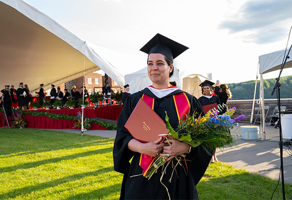image of adult graduate student with diploma and flowers in hand