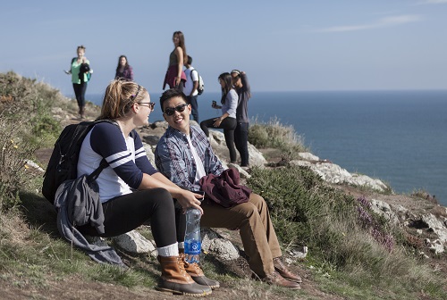 An image of students sitting on a rock.