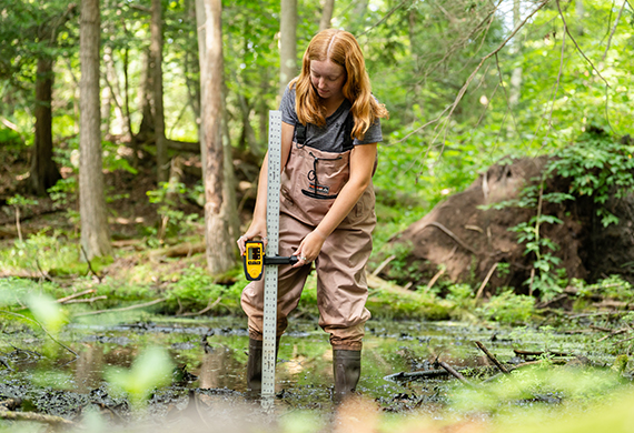 Image of Kristen Fitzgibbon measuring water levels of a vernal pool.