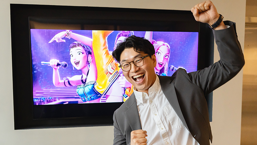 Dr. Sang-Keun Yoo, who teaches with K-Pop, Film, and Dramas this fall, poses for a portrait in front of a TV showing the Kpop Demon Hunters movie. Photo by Nelson Echeverria/Marist University.