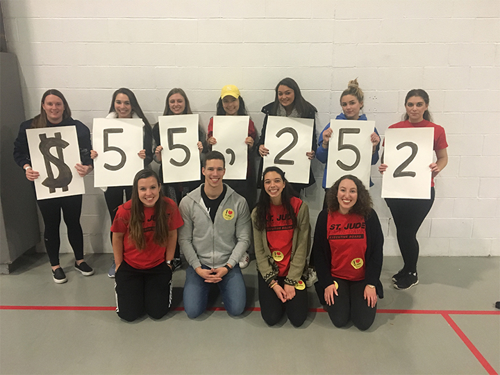 Students hold up signs showing how much money they raised during the Up 'Til Dawn fundraiser