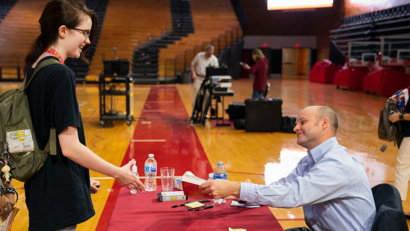 Photo of Jonathan Starr signing his book for a student