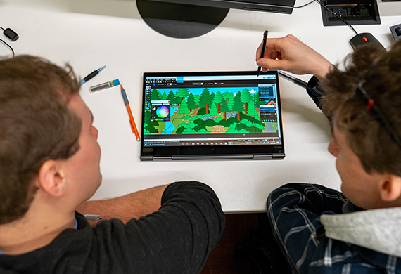 Image of two students working on a tablet that depicts a game design.