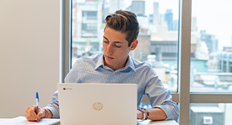 Image of Marist University student sitting at a laptop for Professional Studies degree.