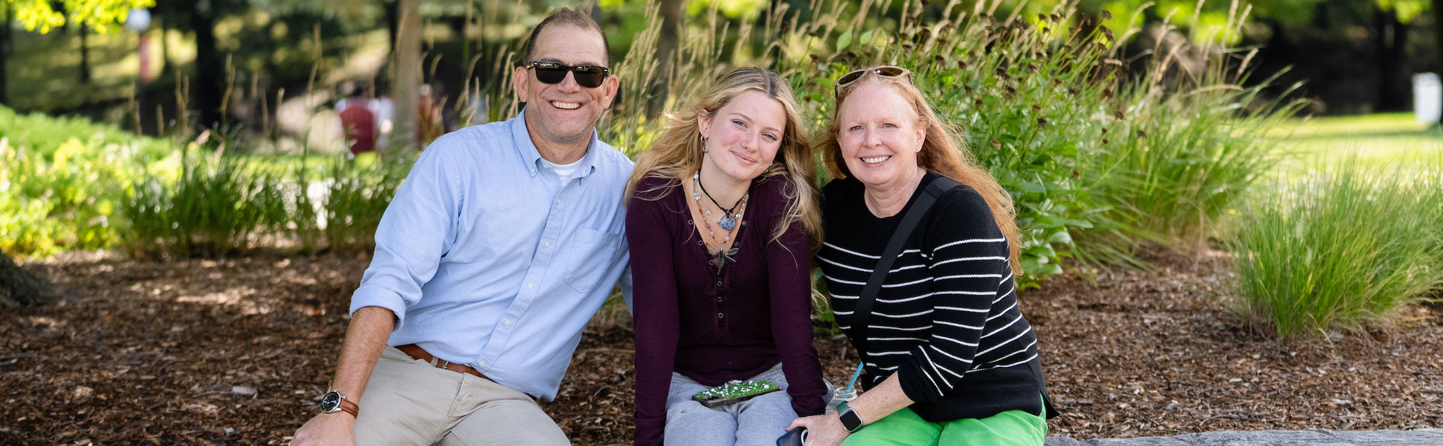 Image of a family sitting under a tree on the Marist University campus.
