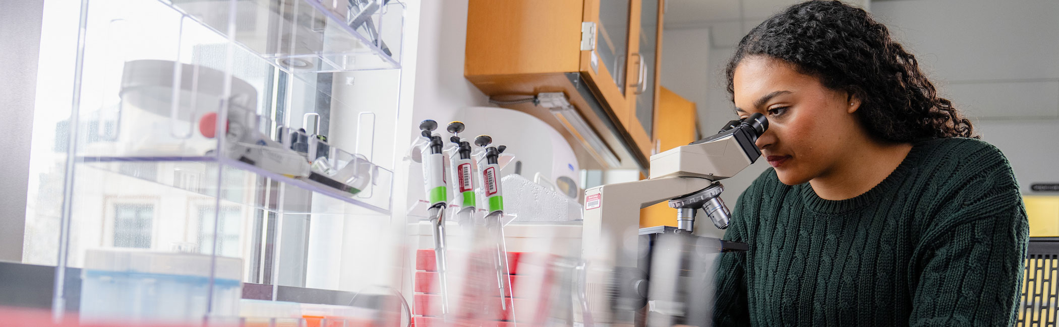 Image of a Marist University science student looking into a microscope.