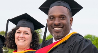 Two recently graduated people smiling at the camera