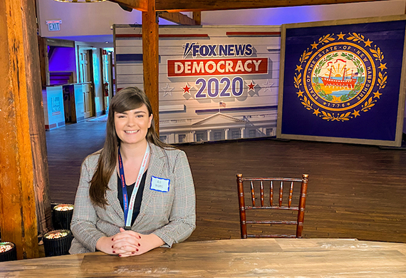 Image of a Marist University student sitting at a reporting desk for Fox News Democracy 2020 in New Hampshire.