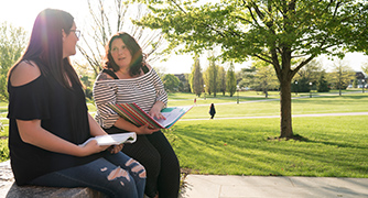 An image of two students working outside. 