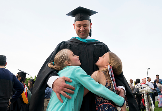 An image of an adult graduate hugging two children.