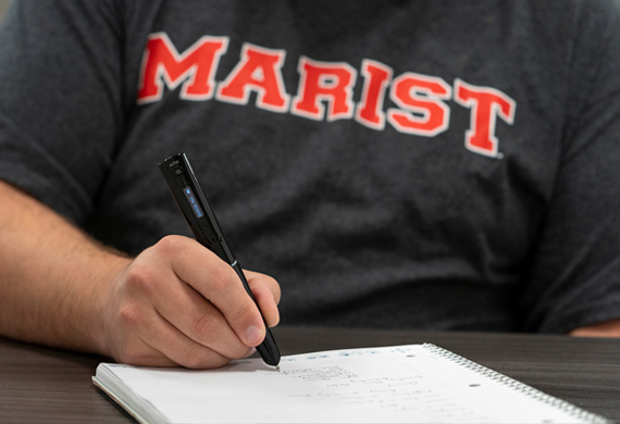 Image of a student with pen writing on notebook paper.