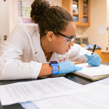 Image of a student taking notes in a laboratory.