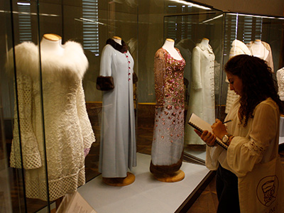 Photo of student writing while looking at a fashion museum