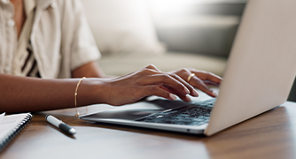 Image of hands typing on a laptop.