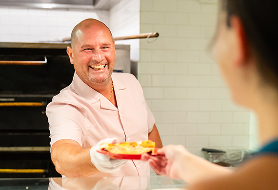 Image of Marist dining staff handing a student a plate of food. 
