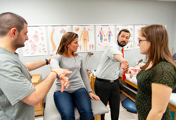 An image of Athletic Training Majors with an Athletic Training Professor demonstrating in an Athletic Training Classroom