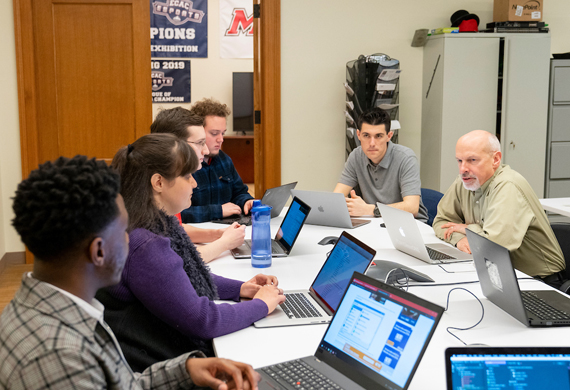 Image of students collaborating with a faculty member in the computer science masters program.