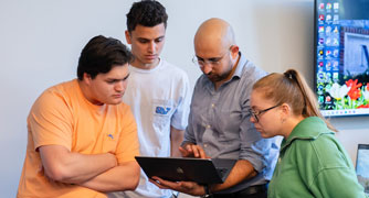 Image of students reviewing research with a faculty member.