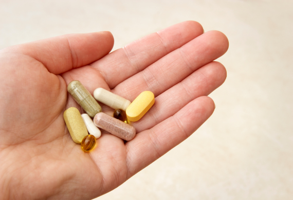 Image of a hand holding various vitamins. 