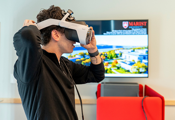 Image of a Marist University student trying on a pair of virtual reality goggles, learning more about artificial intelligence.