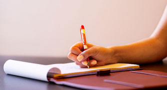 Image of a student writing on a piece of paper