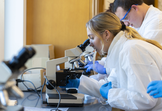 Image of a student looking into a microscope.