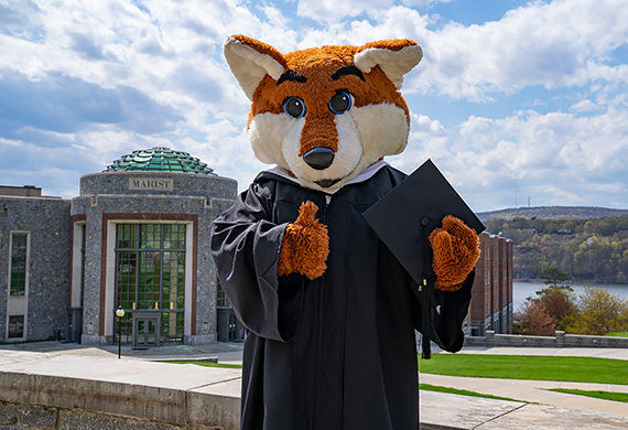 Image of Frankie in a cap and gown in front of the Student Center Rotunda.