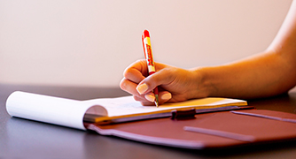 Image of someone writing with a Marist pen