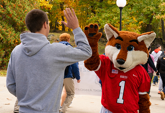 An image of a Marist student hi fiving Frankie the Fox. 