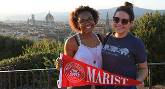 Two girls are posing for a picture with Marist sign