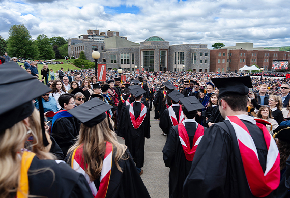 Image students wearing caps and gowns lined up on the Campus Green prior to the undergraduate commencement ceremony.