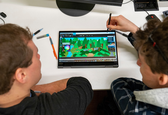 Image of students working together on a graphic design project.