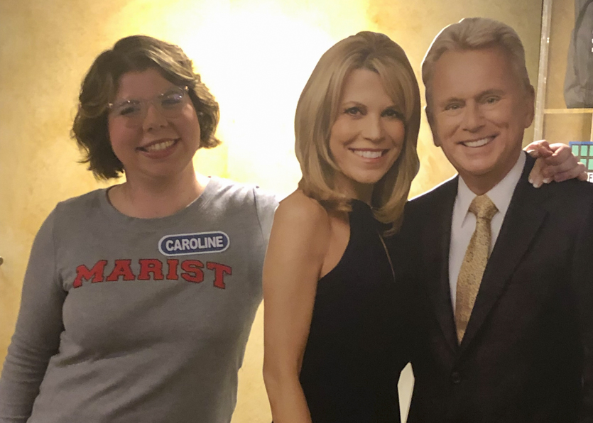 Caroline Fiske '20 poses with cutouts of Vanna White and Pat Sajak from Wheel of Fortune