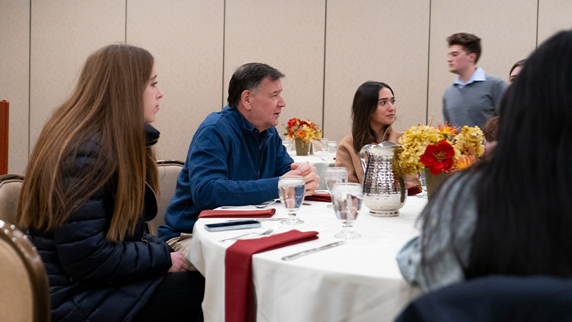Image of Steven Thomma seated at table talking with students.