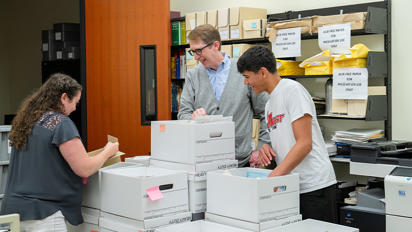 Image of Julius, Elizabeth, and John in the archive with boxes of materials.