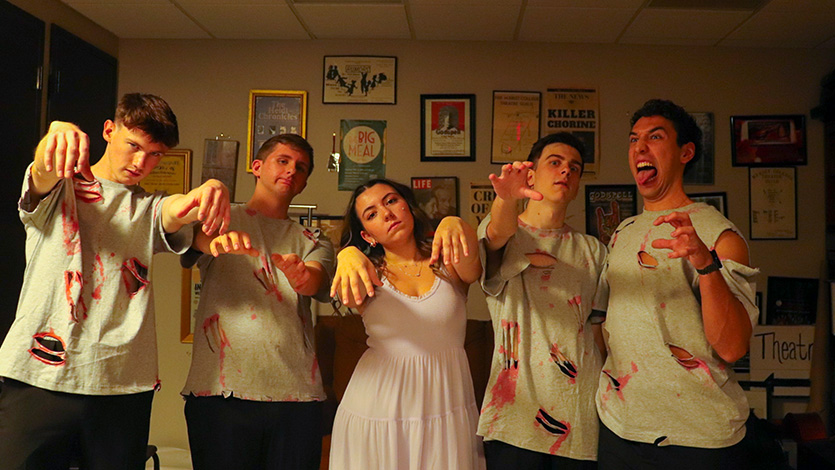 Image of Members of Time Check A cappella backstage alongside stage manager and co-director of the Enharmonics Bella Obligado '26 posing as zombies.