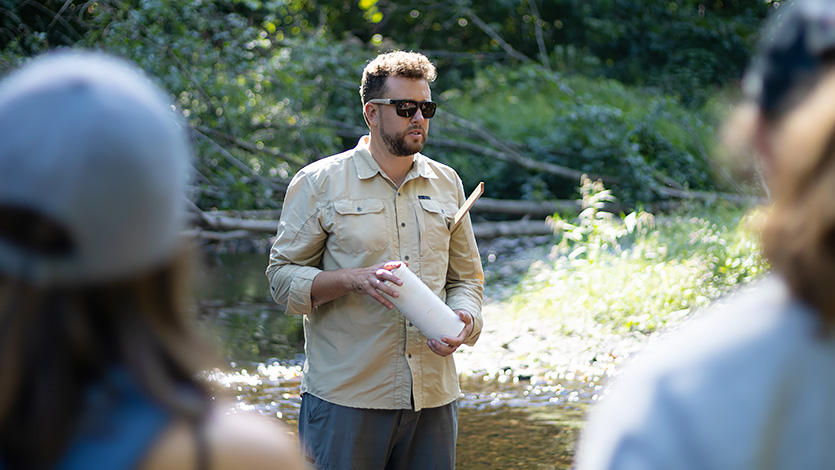 Image of Dr. Zion Klos teaches environmental science students in the stream at Wappingers Creek. Photo by Yasir Olenja ‘24/Marist University.
