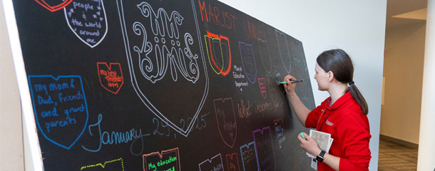 Image of studentsigning the art installation at Marist University Day's experiential learning expo.
