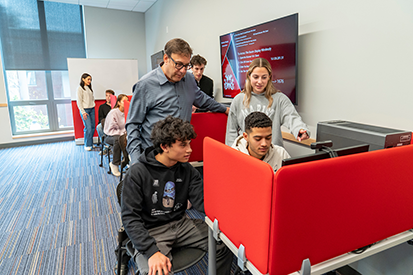 Image of Marist University students huddled around a computer in the marketing lab.
